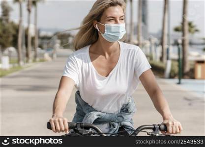 woman riding bike while wearing medical mask