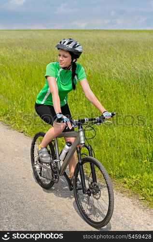 Woman riding her bicycle on countryside road sunny day