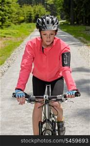 Woman riding mountain bike on sunny countryside cycling path