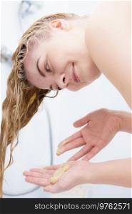 Woman rinsing her hair, washing out of sh&oo having wet blonde hairdo in bathroom.. Woman having wet blonde hair