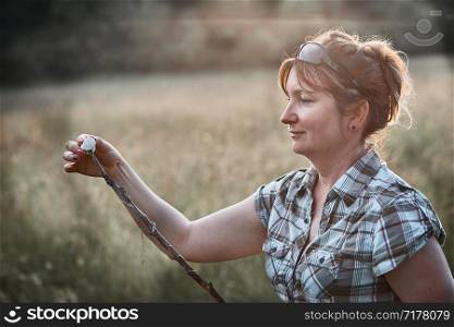 Woman roasting a marshmallow over a campfire on meadow. Vacations close to nature. Candid people, real moments, authentic situations