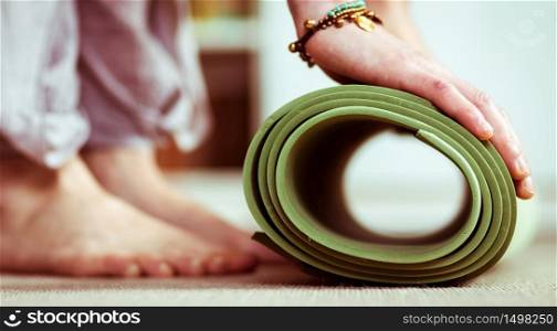 woman rolling a yoga mat at home