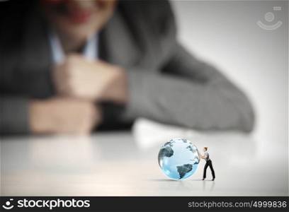 Woman rolling planet. Businesswoman looking at miniature of woman rolling globe