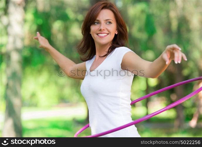 Woman rotates hula hoop on nature background