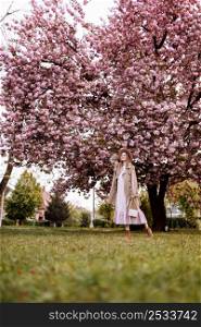 woman&rsquo;s day. Beautiful woman near the sakura trees. Woman in hat, dress and stylish coat. Pink flowers blooming in Uzhhorod, Ukraine. Blossom around. Spring time concept. woman&rsquo;s day. Beautiful woman near the sakura trees. Woman in hat, dress and stylish coat. Pink flowers blooming in Uzhhorod, Ukraine. Blossom around. Spring time concept.