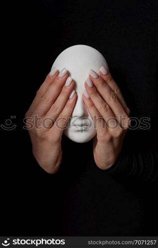 Woman&rsquo;s fingers close eyes of gypsum mask face on a black background. See no evil. Concept three wise monkeys. Place for text.. Girl&rsquo;s hands close eyes of plaster mask face on a black background. See no evil. Concept three wise monkeys.