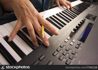 Woman&rsquo;s Fingers with Pencil on Digital Piano Keys