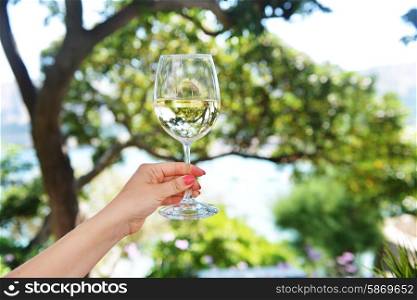 woman&rsquo;s hand holding glass of white wine