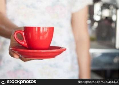 Woman&rsquo;s hand holding red coffee cup, stock photo