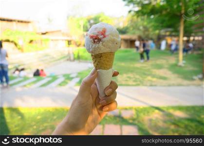 Woman's hand holding wafer cone with berries ice cream.