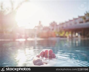 Woman&rsquo;s hand on the background of the pool. Close-up, outdoor. Woman&rsquo;s hand on the background of the pool