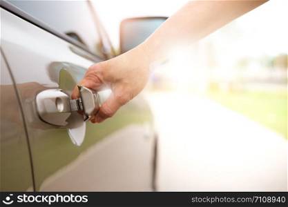 Woman&rsquo;s hand pulling a car&rsquo;s door handle in the park.