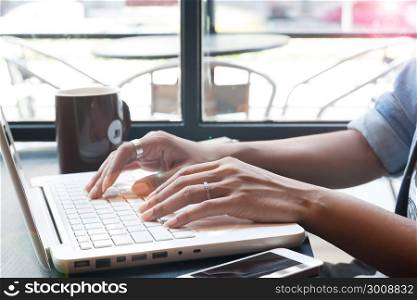 Woman&rsquo;s hand using laptop computer and mobile device in cafe, Online shopping and Technology concept
