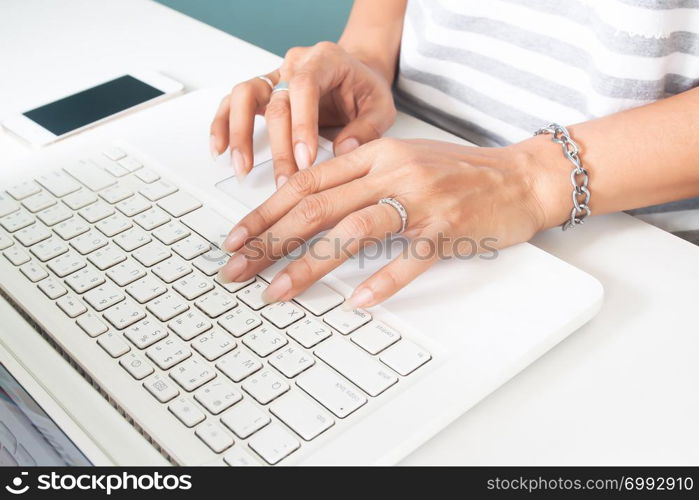 Woman&rsquo;s hand with wedding ring using laptop computer. Technology and lifestyle concept