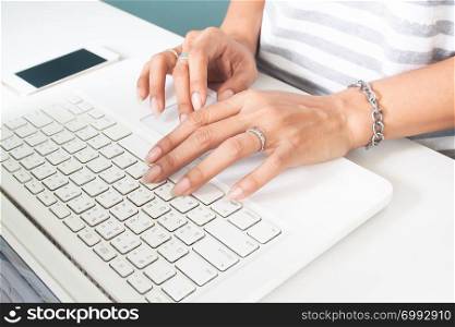 Woman&rsquo;s hand with wedding ring using laptop computer. Technology and lifestyle concept