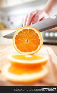 Woman&rsquo;s hands cutting fresh orange on kitchen