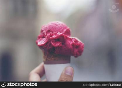 Woman's hands holding melting ice cream waffle cone in hands on summer light