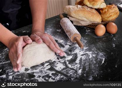 Woman's hands knead dough with flour, eggs and ingredients. at kitchen