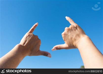 woman&rsquo;s hands showing surfer sign against blue sky background,. woman&rsquo;s hands showing surfer sign against blue sky background