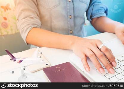 Woman&rsquo;s hands using laptop computer, Airplane model and passport. Woman&rsquo;s hands using laptop computer, Airplane model and passport book on table, Travel concept, Technology lifestyle