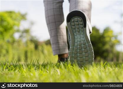 Woman's legs wear sports shoes, Jogging on the green grass in the park at morning, Healthy lifestyle concept