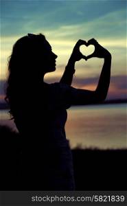 Woman&rsquo;s silhouette making the cute heart gesture
