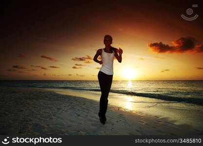 woman run along the sea coast of sunrise behind