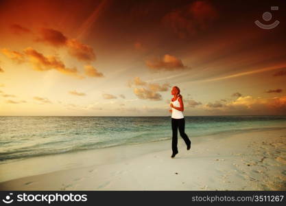 woman run along the sea coast of sunrise behind