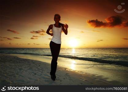 Woman run along the sea coast of sunrise or sunset behind. Woman run at sunset