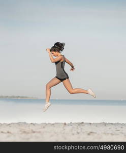 Woman running alone at beautiful sunrise at the beach. Summer sport and freedom concept. Athlete training on dusk.