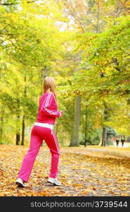 Woman running in autumn fall forest. Female runner training outdoor. Healthy lifestyle young blonde girl jogging outside. Yellow autumnal leaves.