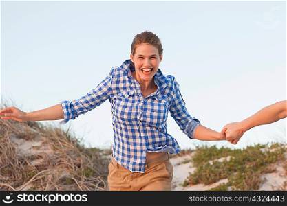 Woman running on beach holding hands with man