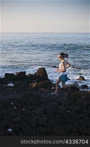 Woman running on rocky beach