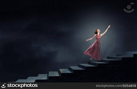 Woman running on stairs. Young blond woman in dress walking up the stairs