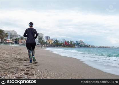 woman running on the beach with black clothes