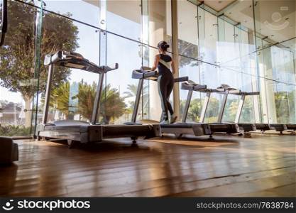 Woman running on treadmill in gym. Ealthy lifestyle.