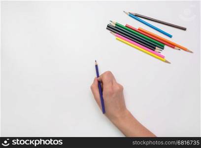 Woman's hand draws a pencil on paper, close-up, top view