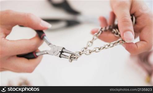 woman s hand fixing metallic hook with pliers