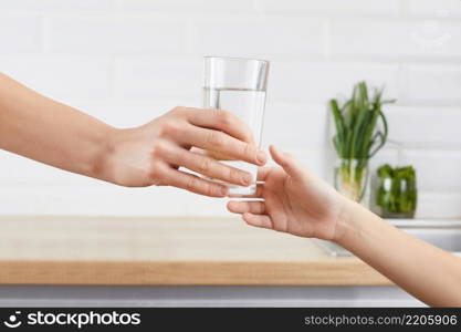 woman’s hand gives a glass of purified water to her child. A concept purification of water. woman’s hand gives a glass of purified water to her child. Concept purification of water