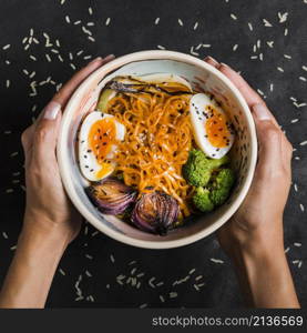 woman s hand holding bowl noodles with eggs onion broccoli bowl black background
