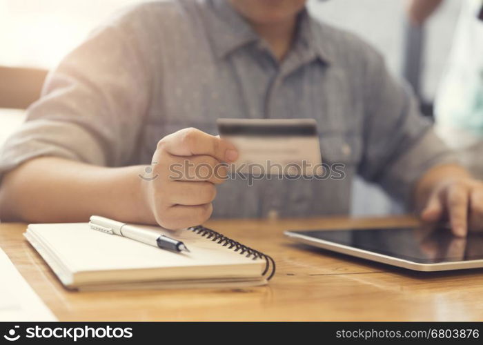 woman's hand holding credit card with tablet for shopping online concept, selective focus and vintage tone