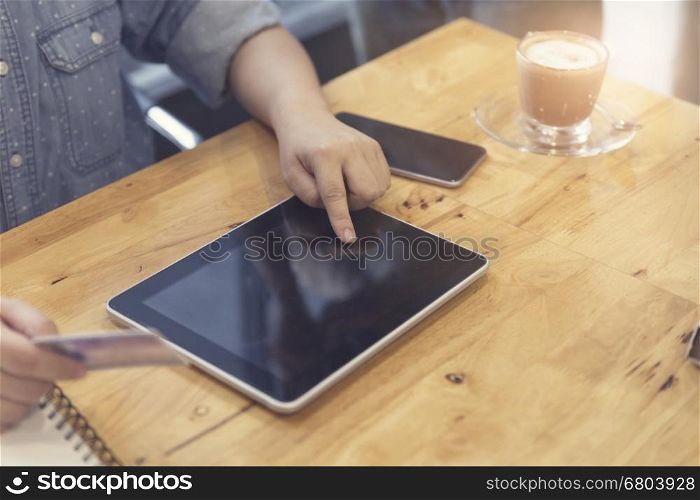 woman's hand holding credit card with tablet for shopping online concept, selective focus and vintage tone