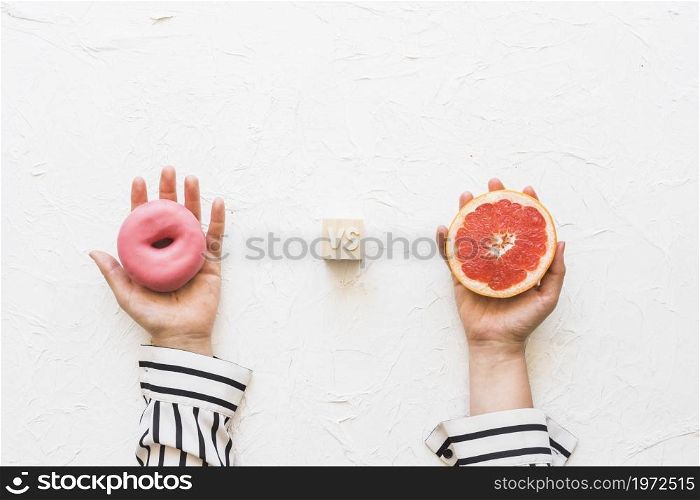 woman s hand holding pink donut versus grapefruit slice textured backdrop. High resolution photo. woman s hand holding pink donut versus grapefruit slice textured backdrop. High quality photo
