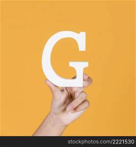 woman s hand holding white capital letter g