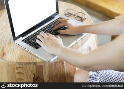 woman's hand on laptop computer notebook with eyeglasses on wooden desk