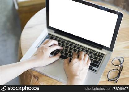 woman's hand on laptop computer notebook with eyeglasses on wooden desk