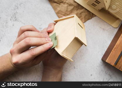 woman s hand smoothing wooden piggybank house