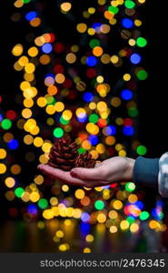 Woman’s hands hold christmas decoration. Christmas and New Year holidays background, winter season with Christmas ornaments and blurred lights