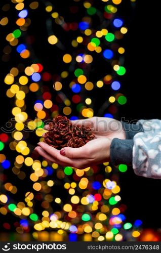 Woman’s hands hold christmas decoration. Christmas and New Year holidays background, winter season with Christmas ornaments and blurred lights