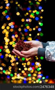 Woman’s hands hold christmas decoration. Christmas and New Year holidays background, winter season with Christmas ornaments and blurred lights